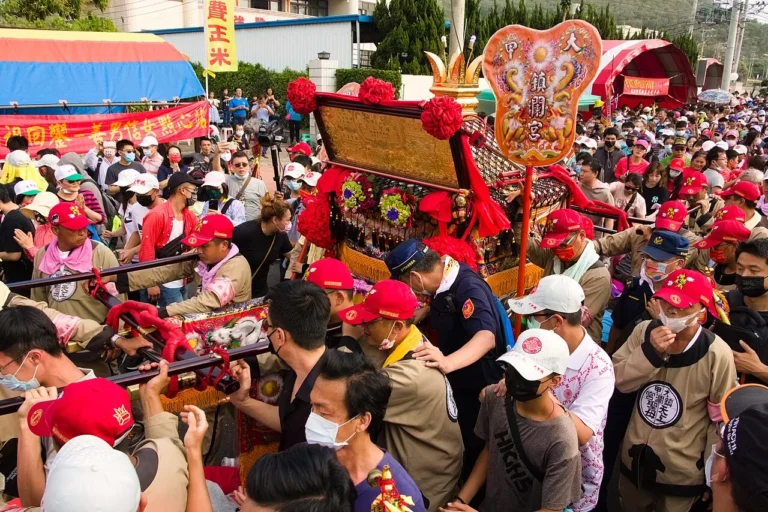 The Dajia Mazu pilgrimage procession on a street in Dajia, Taichung, in April 2021: banners, a marching troupe and crowds of followers around the sedan chair.
